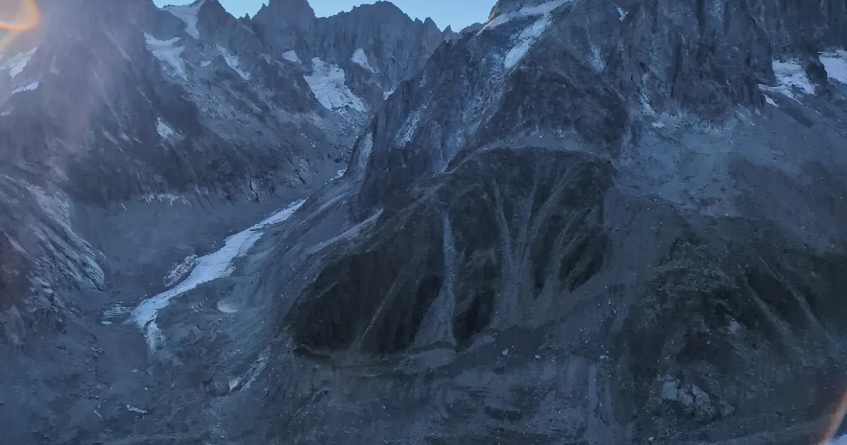 Glacier de haute montagne couvert de moraines sombres, entouré d'arêtes rocheuses enneigées au lever du soleil
